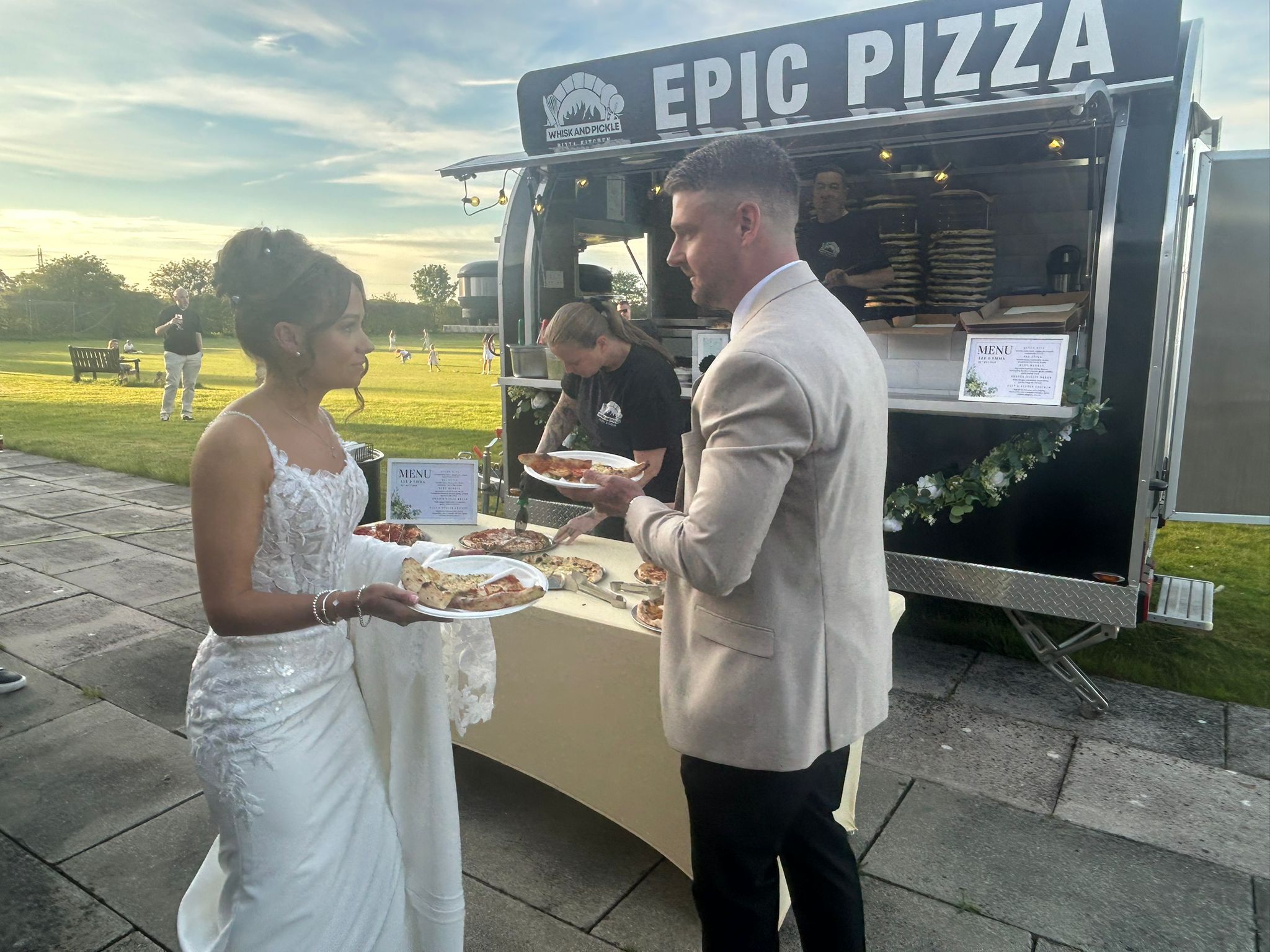 Wedding guests enjoying Whisk And Pickle pizza beside the trailer